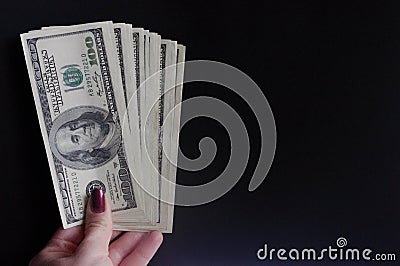 Woman hand hold fan of bills on dark background. Hundred dollars banknotes, pack of money, loan. Stock Photo