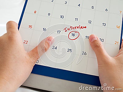 Woman hand hold white calendar with red interview word marked on calendar. Important interview meeting with potential new employer Stock Photo