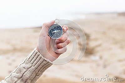 Woman hand holding compass against blurred seashore, beach. Hiking traveler equipment. Navigation for travel. Find way and Stock Photo