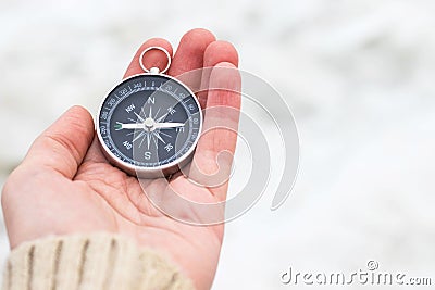 Woman hand holding compass against light blurred background. Hiking traveler equipment. Navigation for travel. Find way and Stock Photo