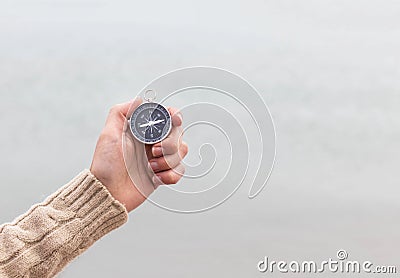 Woman hand holding compass against light blurred seascape. Hiking traveler equipment. Navigation for travel. Find way and Stock Photo