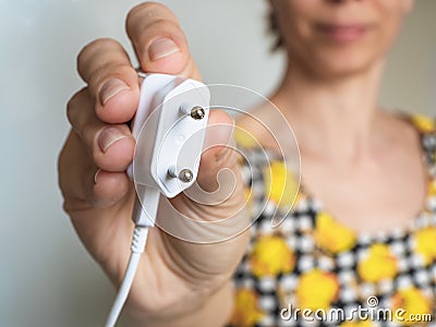 Woman hand holding Electric plug. Close up. Earth Hour saving electrical energy Stock Photo