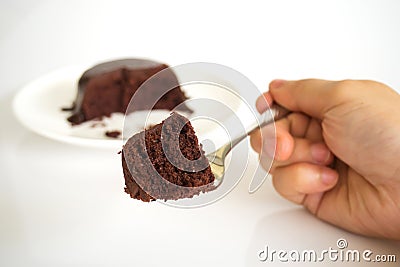 Woman hand holding fork served chocolate cake with chocolate fud Stock Photo