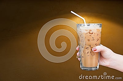 Woman hand holding the glass iced coffee on brown grungy wall Stock Photo