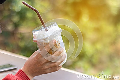 Woman hand holding the glass iced coffee on green nature background. Stock Photo