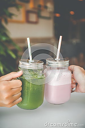 Woman hand holding healthy smoothie in eco friendly glass jar with paper straws in a luxury gym recreation area or vegan Stock Photo