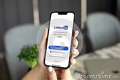 Woman hand holding iPhone 14 with app LinkedIn on screen Editorial Stock Photo
