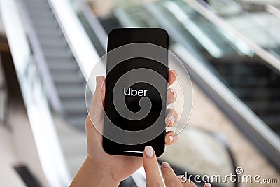 Woman hand holding iPhone 14 with application Taxi Uber screen Editorial Stock Photo