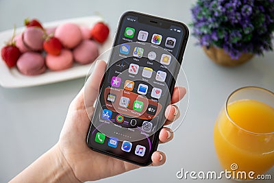 Woman hand holding iPhone 11 with home screen IOS 13 Editorial Stock Photo