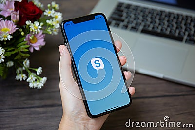 Woman hand holding iPhone X with calling Skype application Editorial Stock Photo