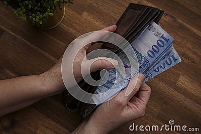 Woman hand holding a leather wallet. Includes Hungarian 1000 forints. Top view of man hand with banknotes Stock Photo