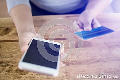 Woman hand holding mobile phone and credit card to paying product in website online shopping on the wooden table Stock Photo