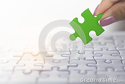 Woman hand holding piece of jigsaw puzzle in green, concept of business teamwork,unity Stock Photo