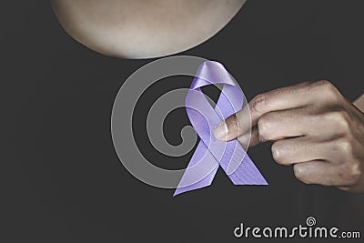 Woman Hand Holding Purple Ribbon, Domestic Violence Awareness Month October concept with deep purple awareness ribbon Stock Photo