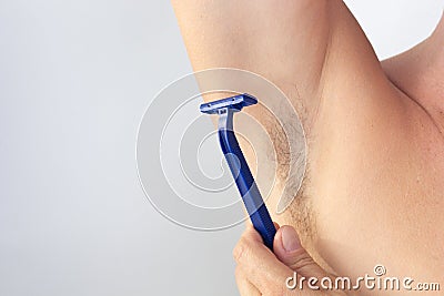 Woman hand holding razor to shave hairy unshaved armpit holding arm aside on the white background Stock Photo