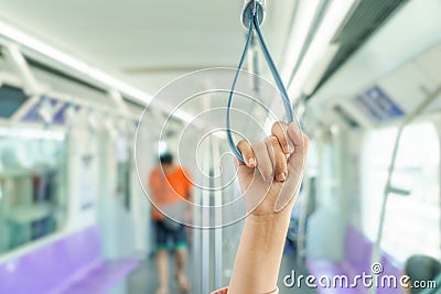 Woman hand holding the train rails while taking sky train. Stock Photo