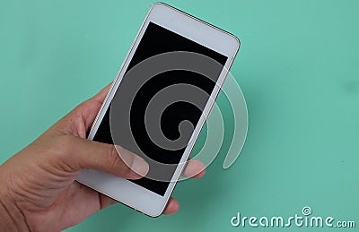 Woman hand holding the white smartphone with blank screen and modern design isolated on green pastel background Stock Photo