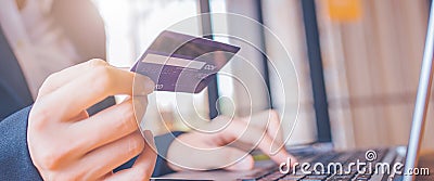 Woman hand holds a blue credit card.And are using a laptop computer.Web banner Stock Photo