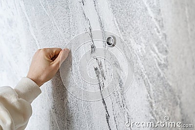 Woman hand knocking on grey door standing in the doorway Stock Photo