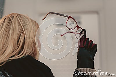 Woman hand in leather glove holding red rimmed glasses Stock Photo