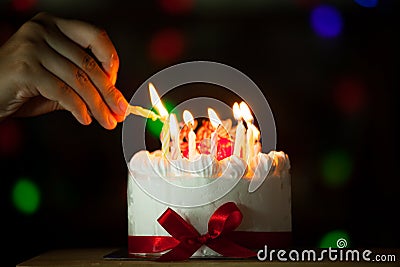 Woman hand lighting candle on birthday cake Stock Photo