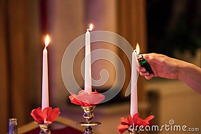 Woman hand lightning candles on Banquet with red table setting Stock Photo