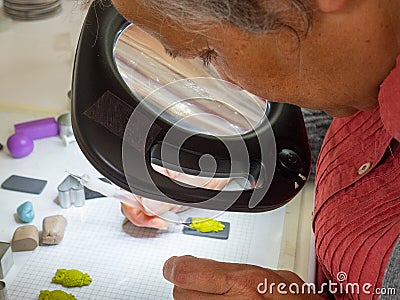 Woman hand making owl button from polymer clay. Hobby, handicraft background. Stock Photo