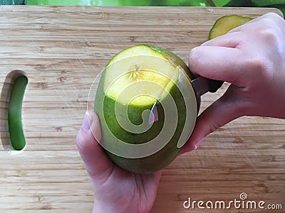 Woman hand peeling a mango fruit with the knife Stock Photo