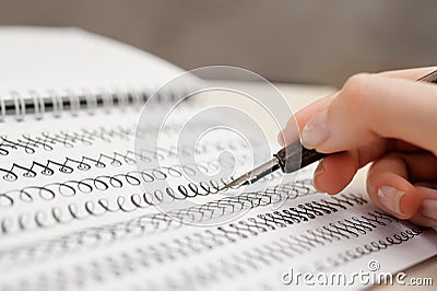 Woman hand with pen for calligraphy writing in a notebook Stock Photo