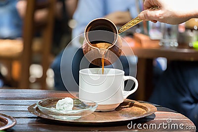Woman pouring Greek coffee on a white cup. Stock Photo