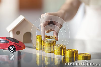 Woman hand putting money coin stack with wooden house and red car mortgage, Property investment financial. Saving money for buy Stock Photo