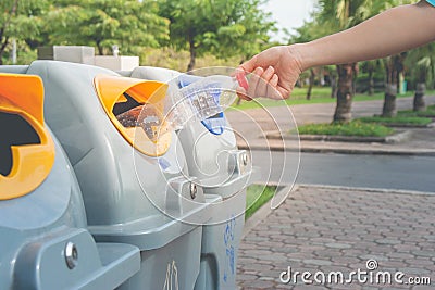 Woman hand putting used plastic bottle in public recycle bins or segregated waste bins in public park. Stock Photo