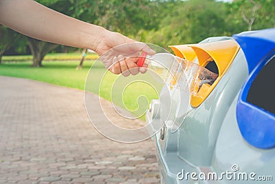 Woman hand putting used plastic bottle in public recycle bins or segregated waste bins in public park. Stock Photo