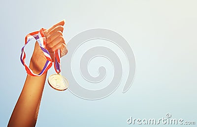 Woman hand raised, holding gold medal against sky. award and victory concept Stock Photo