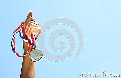 Woman hand raised, holding gold medal against skyl. award and victory concept. selective focus. retro style image. Stock Photo