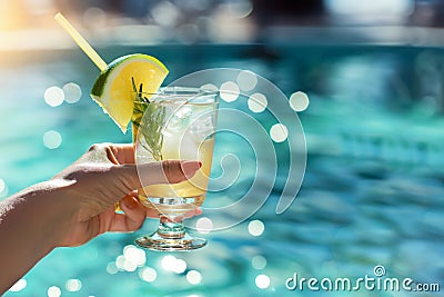 Woman hand with refreshing lemon cocktail, in swimming pool Stock Photo