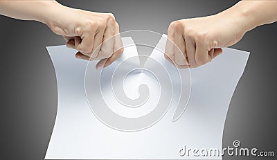 Woman hand ripping white paper on gray background Stock Photo