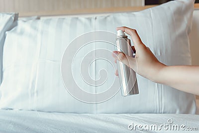 Woman Hand is Spraying Air Freshener into Pillow on Bedroom, Unpleasant Smell and Aromatherapy Concept Stock Photo