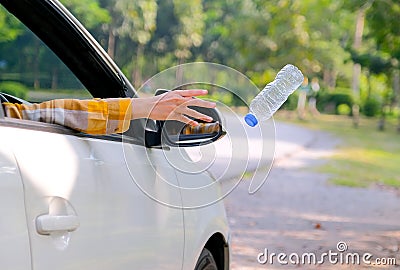 Woman hand throw clear bottle with blue cap out from car window with the concept human garbage destroy environment Stock Photo