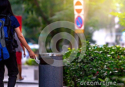 Woman hand throwing twisted empty water bottle in recycle bin. Gray plastic recycle bin. Backpacker discard bottle in trash bin. Editorial Stock Photo