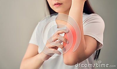 Woman hand touching elbow from chronic joint rheumatism and there is so much suffering. on the gray background. Stock Photo