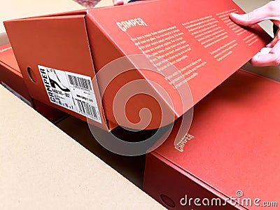 Woman hand unboxing unpacking new brand modern Camper box shoes Editorial Stock Photo