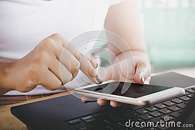 Woman hand using smart phone and computer laptop for her work, Stock Photo