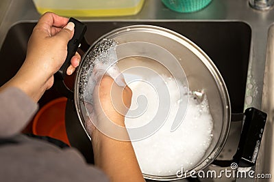 Woman hand washing stainless steel pot with dish washing soap Stock Photo