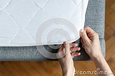 Woman hand wearing topper at orthopedic mattress Stock Photo