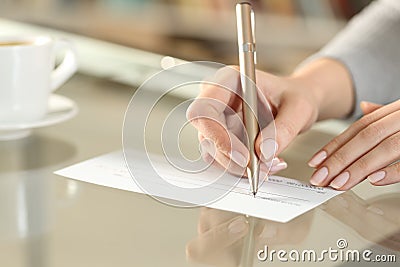 Woman hand writing bank check to make a payment Stock Photo