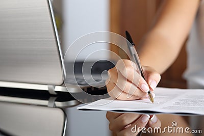 Woman hand writing a contract with a laptop beside Stock Photo