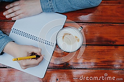 Woman hand writing journal on small notebook while drinking coffee, top view Stock Photo