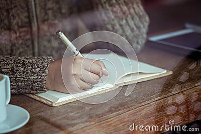 Woman hand writing on notebook in the cafe in rainy day Stock Photo