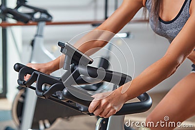 Woman hands on a bar stationary bike the gym Stock Photo